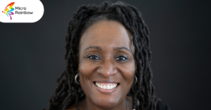 A middle aged black woman with locs, smiling at the camera
