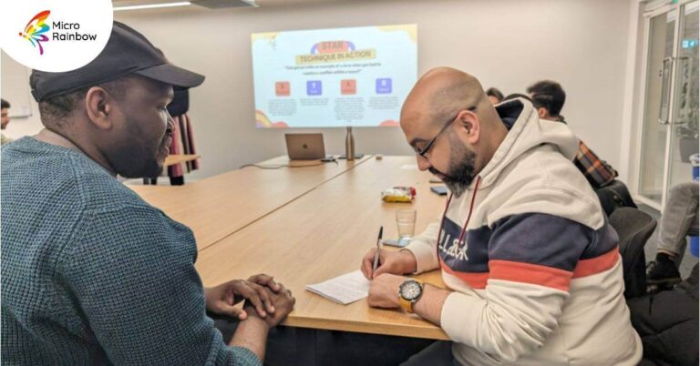 Two people taking notes at a Micro Rainbow employment support workshop.