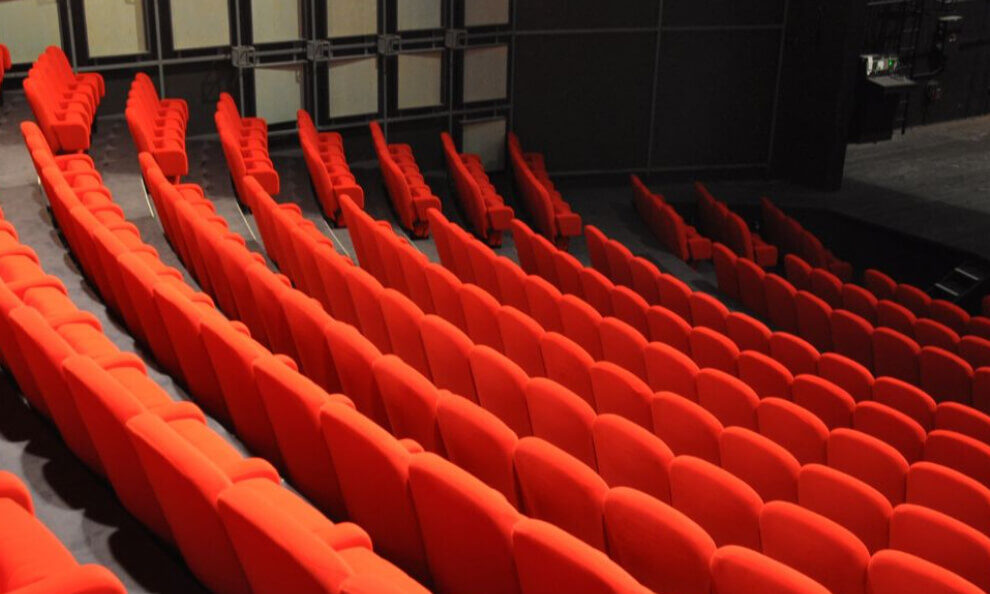 A theatre interior featuring vibrant orange seats against a sleek black wall.