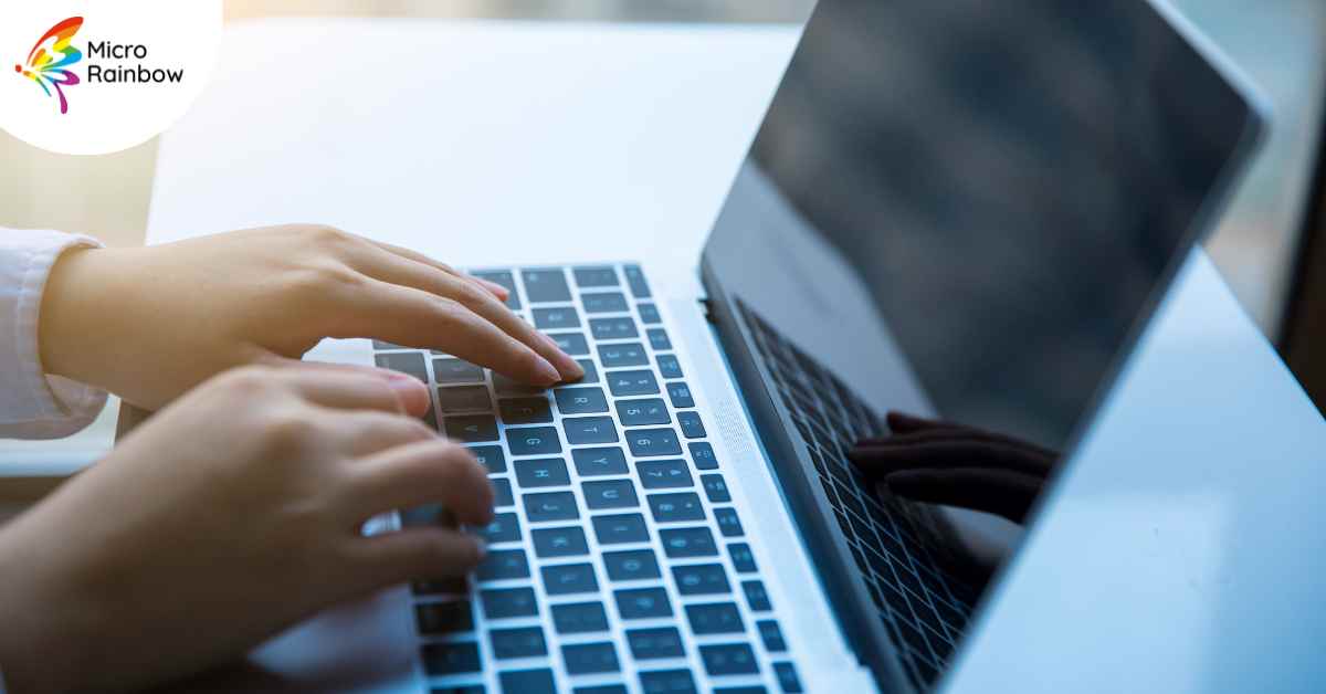 A close-up of hands typing on a laptop.