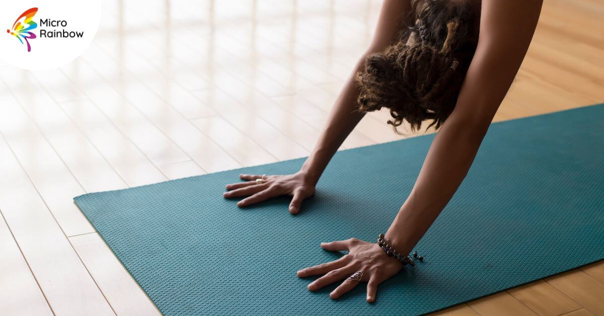 A person in a yoga pose with their hands and head visible.