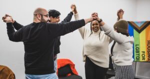 Participants holding hands at the Micro Rainbow community theatre workshop.