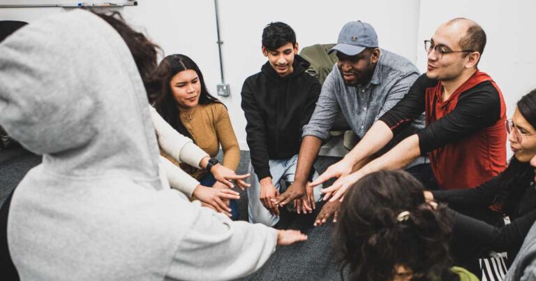 Participants at the Micro Rainbow theatre workshop extending hands toward each other in a circle.
