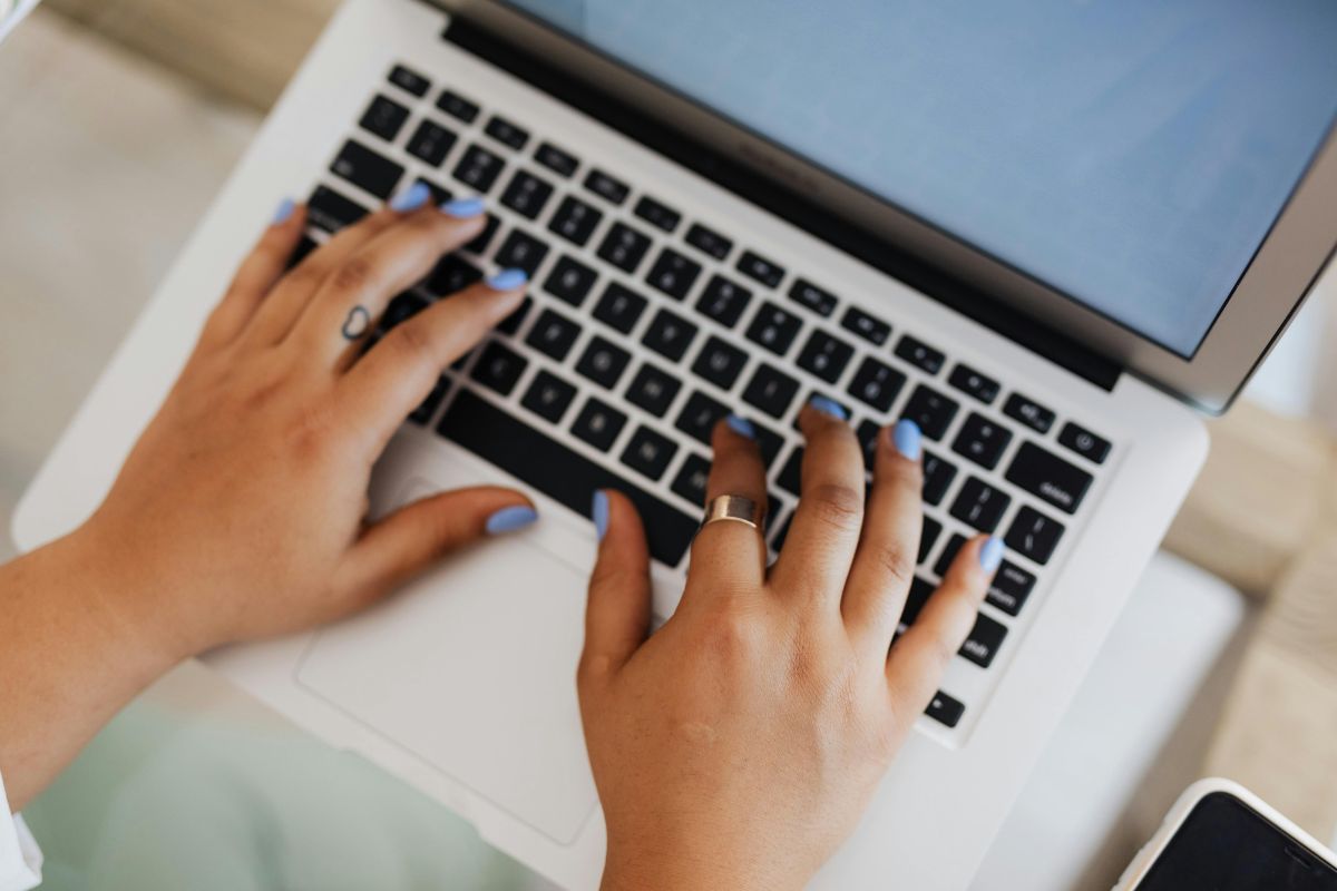 Hands working on a laptop from above